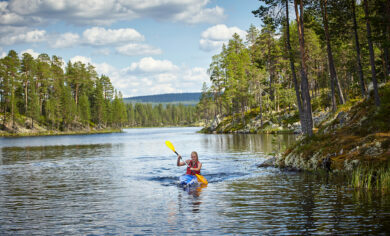 Frau im Kanu auf Fluss in Schweden mit Rucksack Reisen